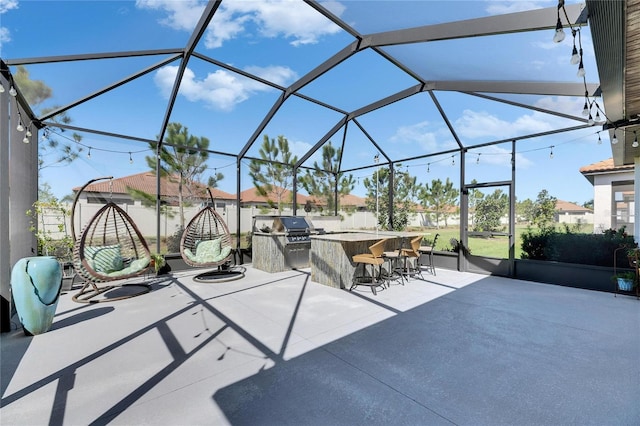 view of patio / terrace featuring outdoor dry bar, grilling area, glass enclosure, and an outdoor kitchen