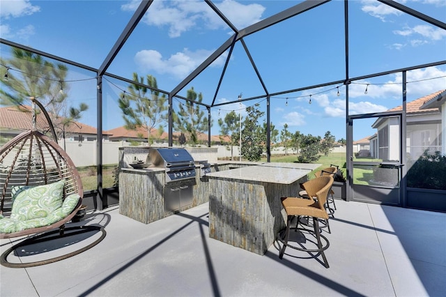 view of patio / terrace featuring outdoor dry bar, fence, a lanai, exterior kitchen, and a grill