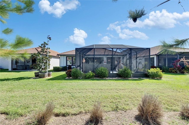 rear view of house with glass enclosure, a yard, stucco siding, and a tiled roof