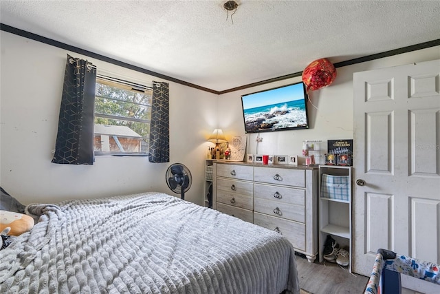 bedroom with crown molding, wood finished floors, and a textured ceiling