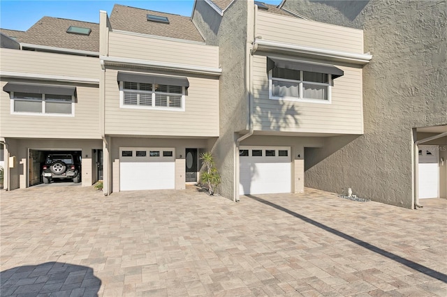 townhome / multi-family property with stucco siding, a garage, and driveway