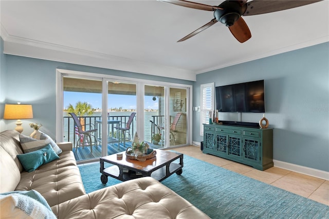 living area with tile patterned flooring, ceiling fan, crown molding, and baseboards