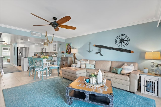 living room with light tile patterned flooring, visible vents, crown molding, and a ceiling fan