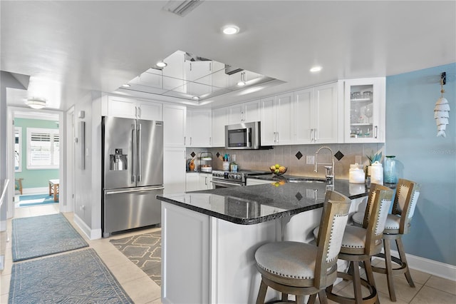 kitchen featuring visible vents, decorative backsplash, a peninsula, stainless steel appliances, and a raised ceiling