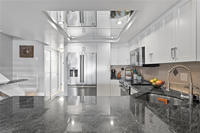 kitchen featuring visible vents, a sink, decorative backsplash, white cabinets, and high quality appliances