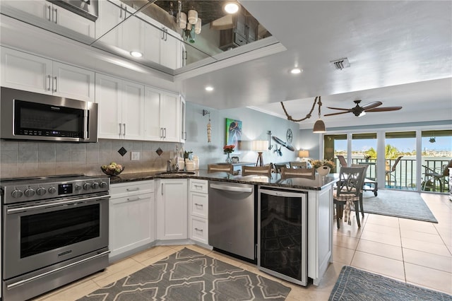 kitchen featuring beverage cooler, light tile patterned floors, white cabinetry, and stainless steel appliances