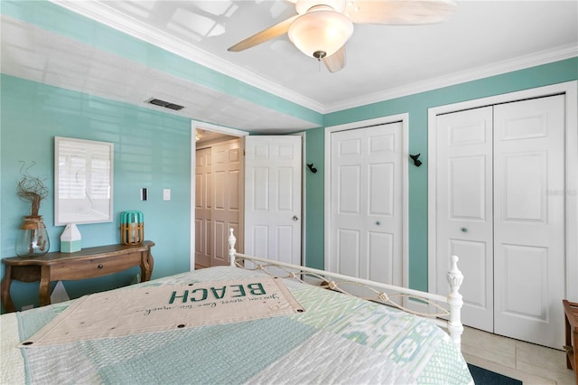 tiled bedroom with visible vents, a ceiling fan, multiple closets, and ornamental molding