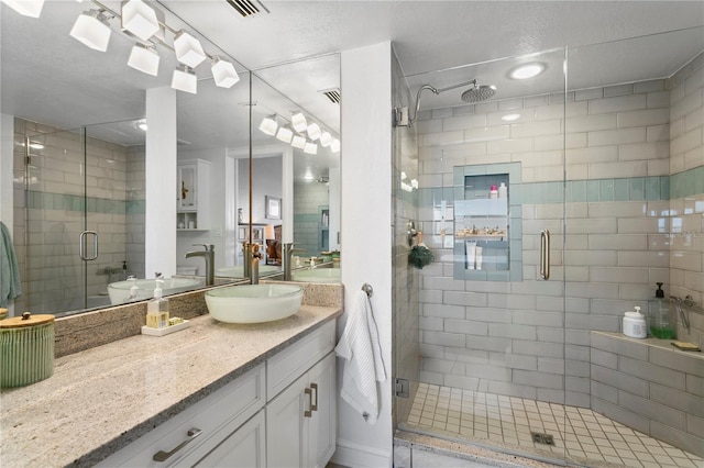 full bathroom featuring vanity, a shower stall, and visible vents