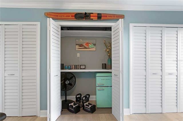 washroom featuring laundry area, light wood-style flooring, baseboards, and ornamental molding