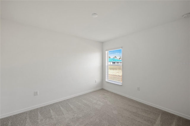 spare room featuring baseboards and light colored carpet