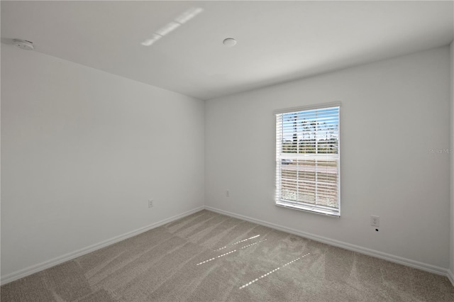 unfurnished room featuring light colored carpet and baseboards