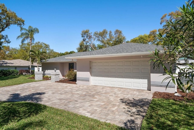 view of front of property with a front yard, roof with shingles, stucco siding, decorative driveway, and an attached garage