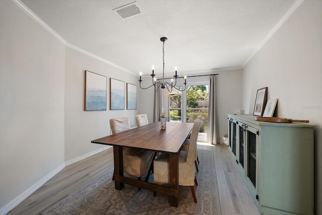 dining room with visible vents, an inviting chandelier, wood finished floors, and crown molding