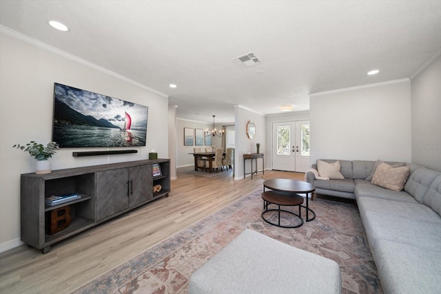 living room with visible vents, an inviting chandelier, ornamental molding, french doors, and light wood-type flooring