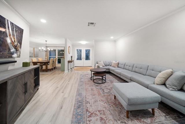 living room with visible vents, light wood finished floors, ornamental molding, french doors, and a notable chandelier