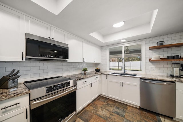 kitchen featuring decorative backsplash, appliances with stainless steel finishes, a raised ceiling, and a sink