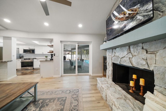 living area featuring a ceiling fan, baseboards, light wood finished floors, recessed lighting, and a fireplace