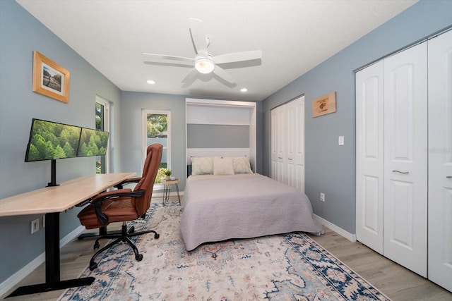 bedroom featuring recessed lighting, baseboards, multiple closets, and wood finished floors