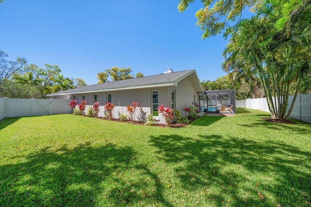 rear view of property with a yard, a fenced backyard, and stucco siding