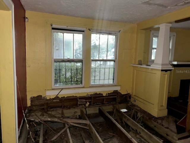 miscellaneous room with decorative columns and a textured ceiling