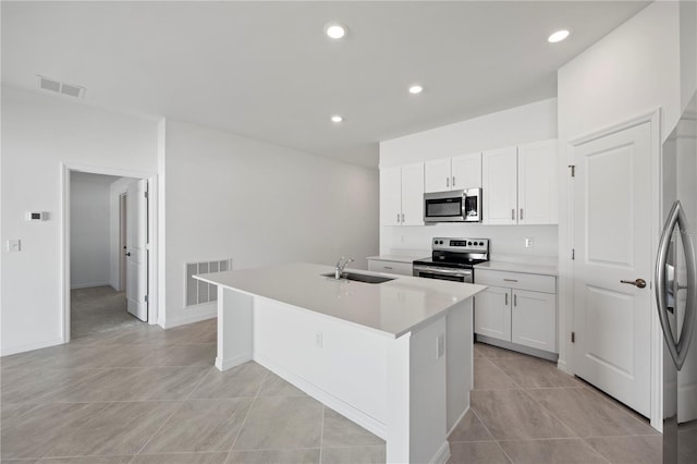 kitchen with a sink, visible vents, appliances with stainless steel finishes, and an island with sink