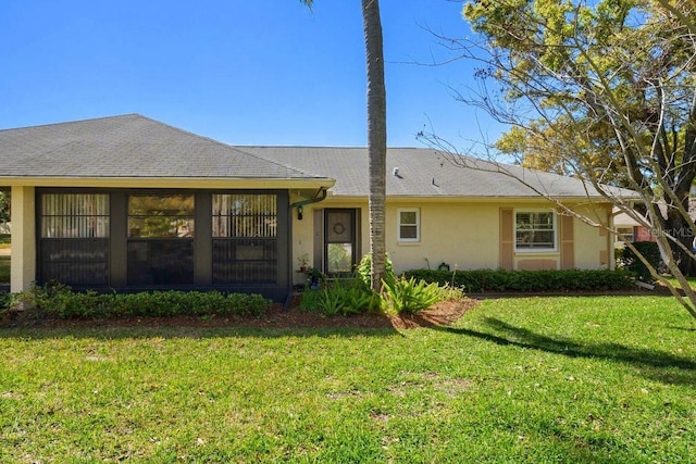 back of house with stucco siding, a lawn, and a shingled roof