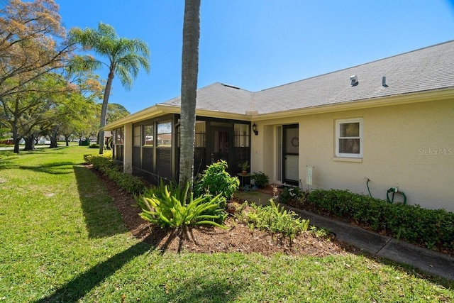 exterior space with stucco siding, a yard, and roof with shingles