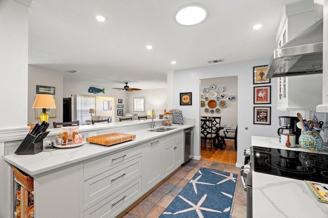 kitchen with a peninsula, stainless steel appliances, a sink, extractor fan, and white cabinets