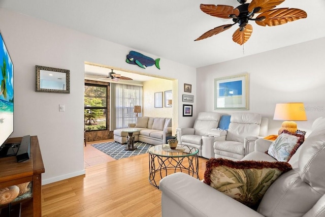 living area featuring light wood-type flooring, baseboards, and a ceiling fan