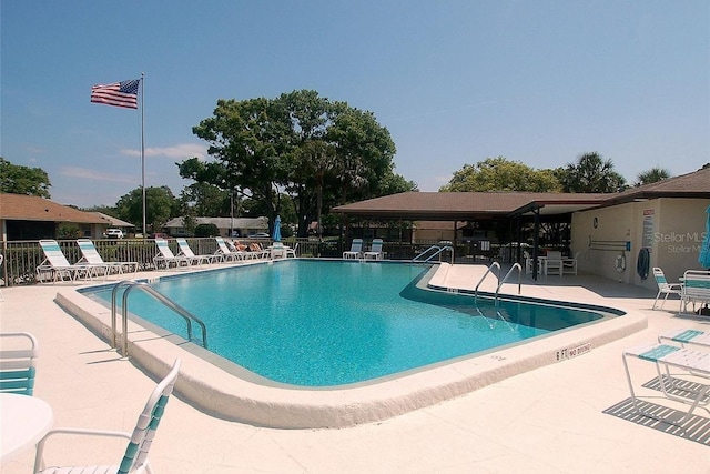 community pool with a patio area and fence