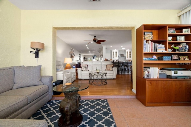 living area featuring tile patterned flooring, visible vents, and a ceiling fan