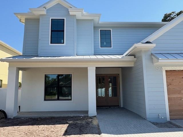 doorway to property featuring french doors, a standing seam roof, and metal roof
