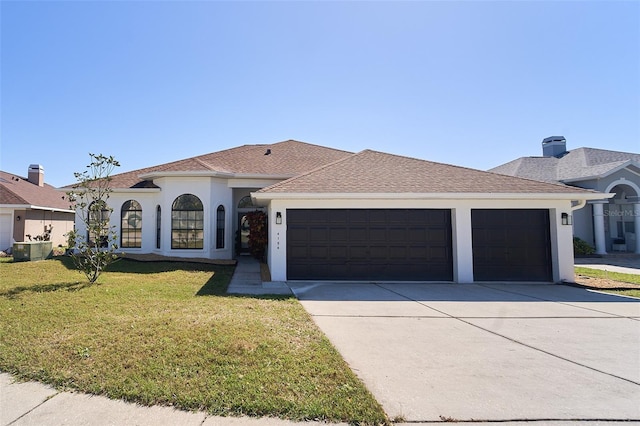 mediterranean / spanish house with stucco siding, roof with shingles, concrete driveway, a front yard, and an attached garage