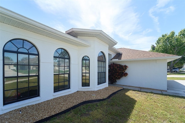 view of side of property with stucco siding and roof with shingles