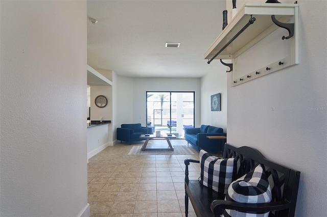 living area with light tile patterned floors, visible vents, and baseboards