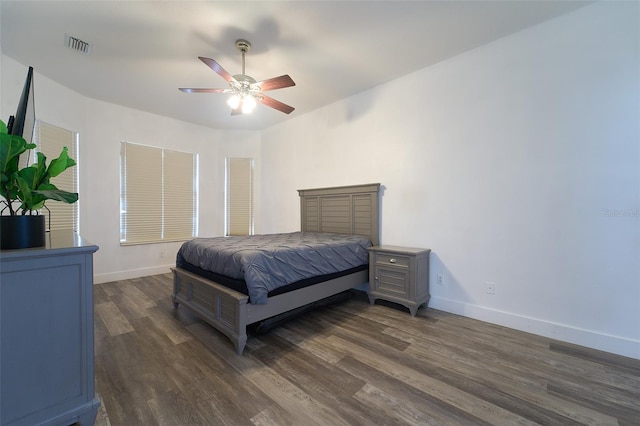 bedroom with visible vents, baseboards, dark wood finished floors, and a ceiling fan