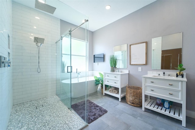 bathroom featuring a tile shower, a freestanding tub, and two vanities