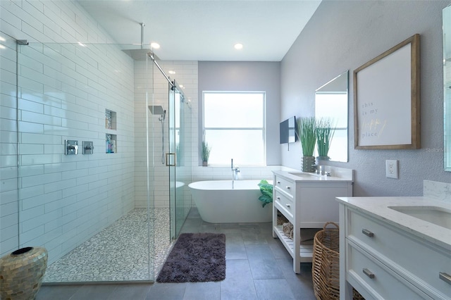 full bath with a sink, a freestanding bath, two vanities, and a shower stall