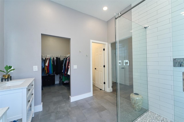 full bathroom with a walk in closet, a shower stall, vanity, and baseboards