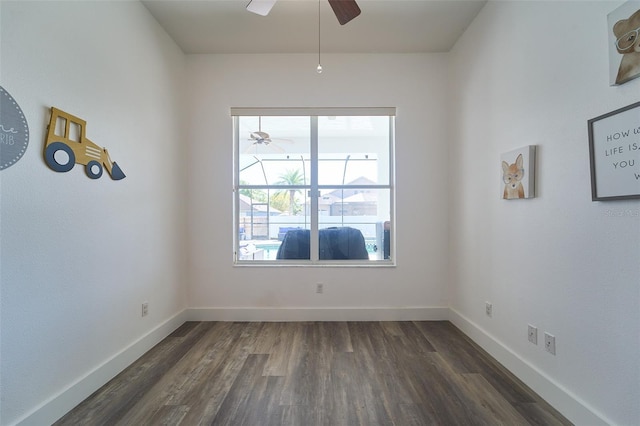 spare room with dark wood finished floors, baseboards, and a ceiling fan