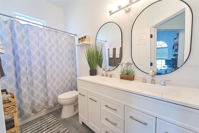 bathroom with double vanity, toilet, and a sink