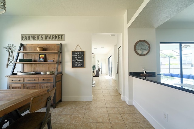 corridor featuring light tile patterned floors and baseboards