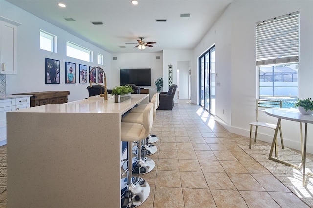 kitchen with light tile patterned floors, visible vents, plenty of natural light, and white cabinetry