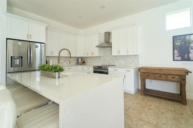 kitchen with wall chimney range hood, tasteful backsplash, white cabinets, and stainless steel appliances