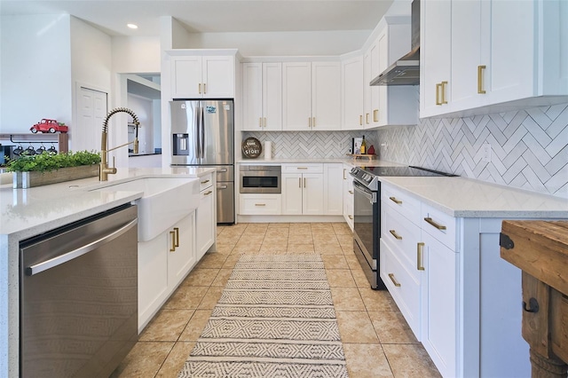 kitchen with light tile patterned floors, a sink, stainless steel appliances, wall chimney range hood, and tasteful backsplash