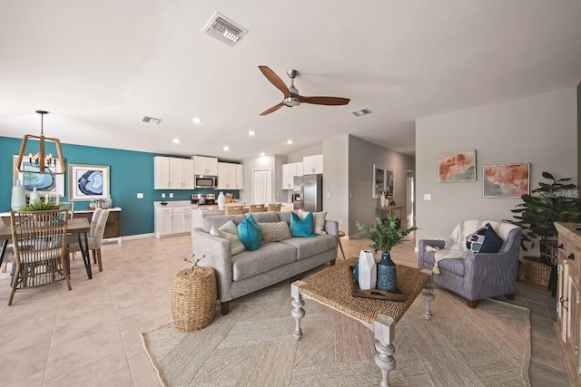 living room featuring light tile patterned floors, visible vents, ceiling fan with notable chandelier, and recessed lighting