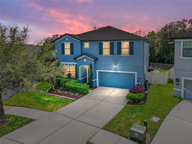 traditional home featuring fence, concrete driveway, a front yard, stucco siding, and an attached garage