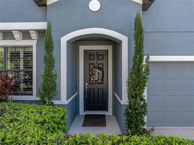 property entrance with a garage and stucco siding