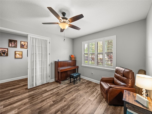 living area featuring baseboards, a textured ceiling, wood finished floors, and a ceiling fan