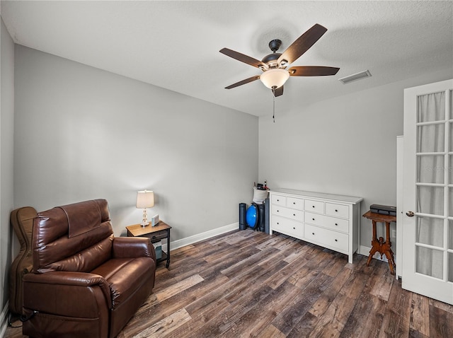 sitting room featuring visible vents, a ceiling fan, a textured ceiling, baseboards, and dark wood-style flooring